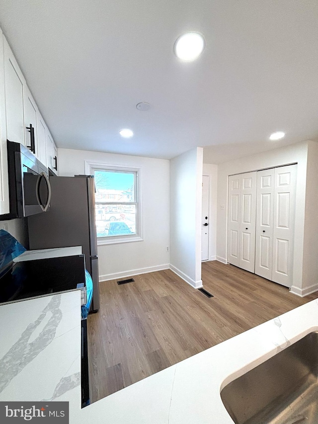 kitchen featuring light wood-type flooring, white cabinetry, and electric range oven