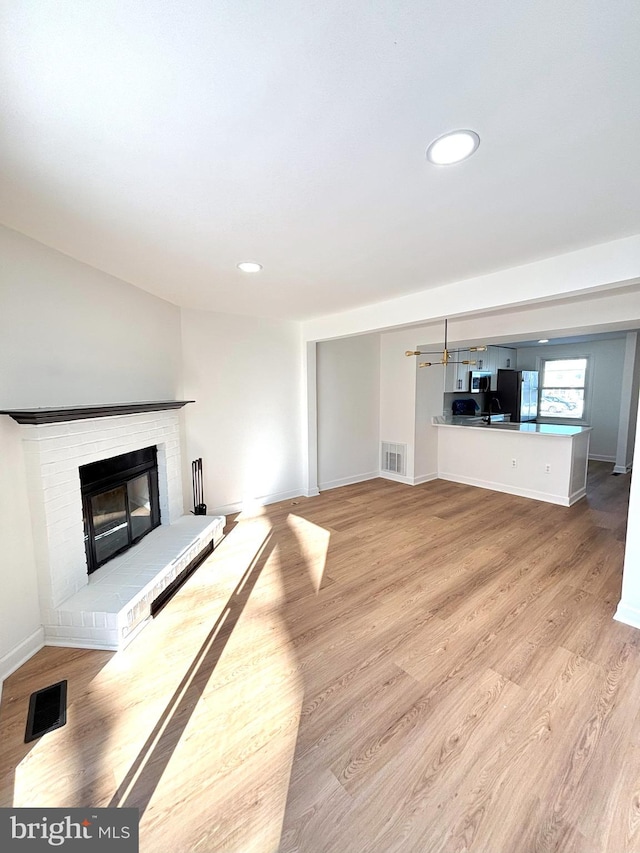 unfurnished living room featuring light wood-type flooring and a fireplace