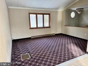 unfurnished room with crown molding, a baseboard radiator, and carpet flooring