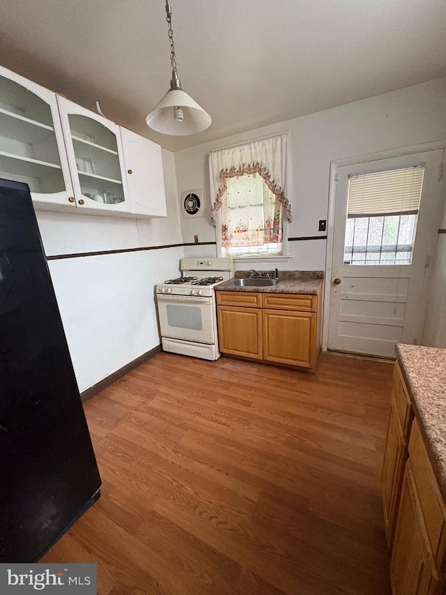 kitchen featuring decorative light fixtures, sink, light wood-type flooring, and white gas stove