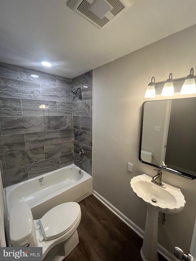 full bathroom featuring tiled shower / bath combo, wood-type flooring, sink, and toilet