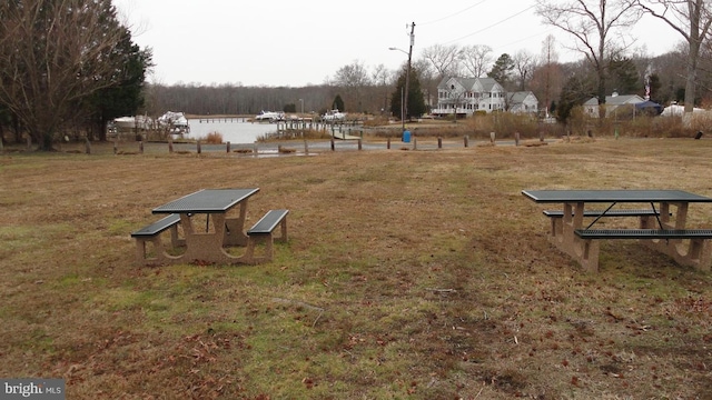 surrounding community with a water view and a lawn