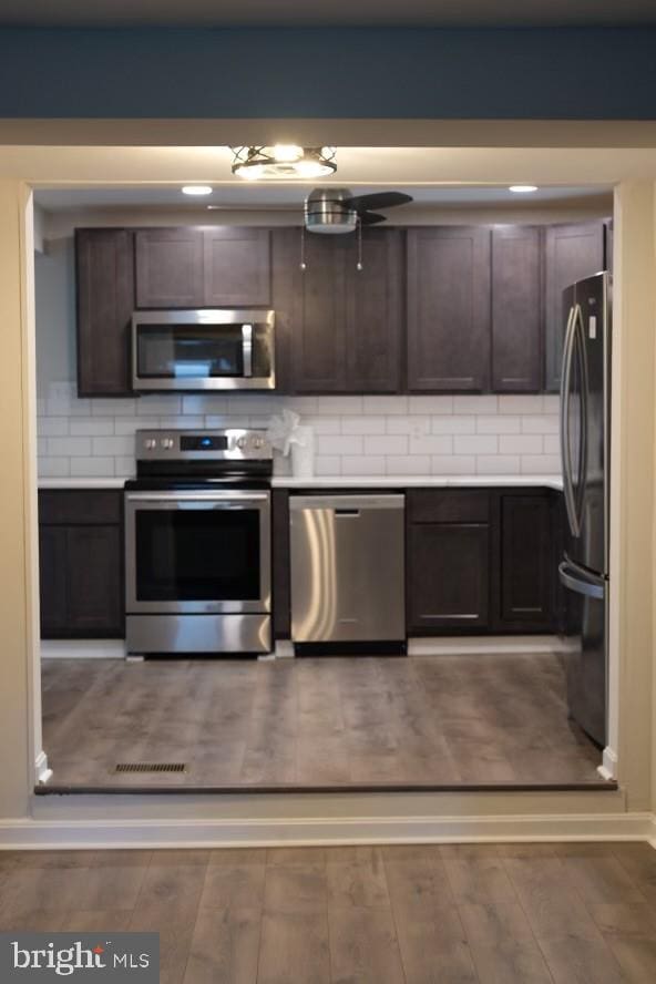 kitchen featuring stainless steel appliances, dark brown cabinets, dark hardwood / wood-style floors, and decorative backsplash