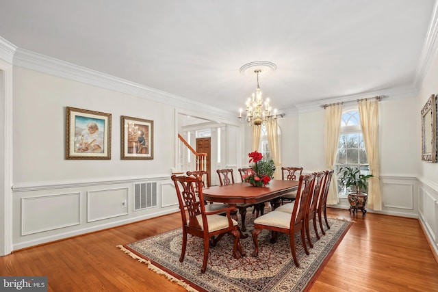 dining space with a chandelier, ornamental molding, and hardwood / wood-style flooring