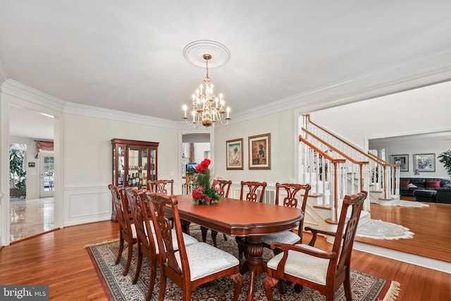 dining room featuring ornamental molding, hardwood / wood-style flooring, and a notable chandelier