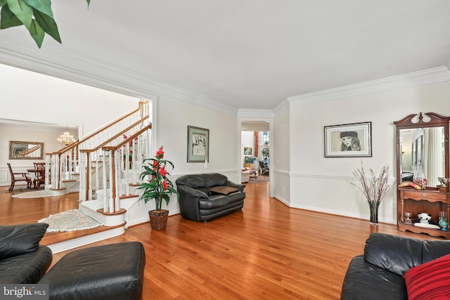 living room with a notable chandelier, ornamental molding, and hardwood / wood-style flooring