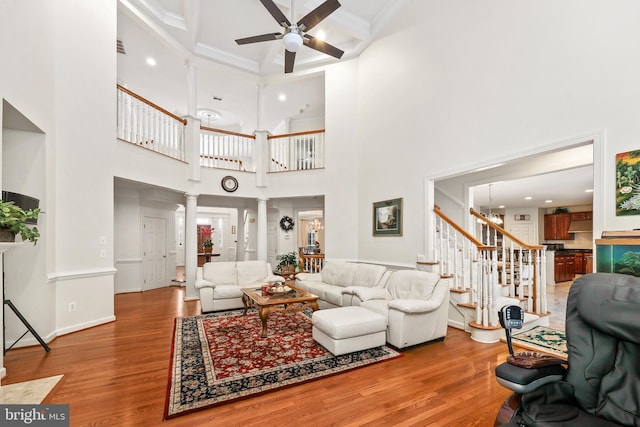 living room featuring crown molding, ceiling fan, a high ceiling, and decorative columns