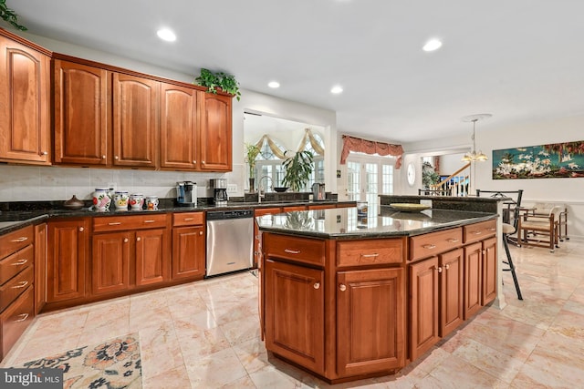 kitchen with dishwasher, dark stone countertops, a center island, pendant lighting, and sink