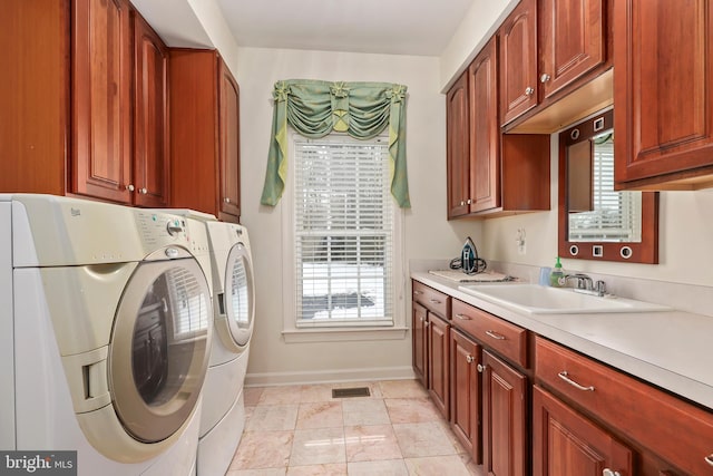 clothes washing area featuring light tile patterned floors, cabinets, washer and clothes dryer, and sink