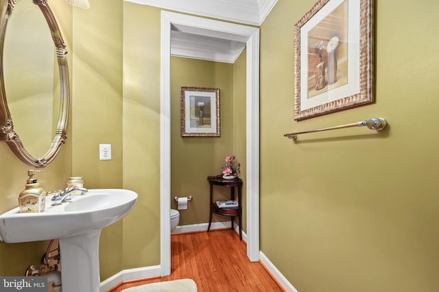 bathroom with toilet, ornamental molding, and hardwood / wood-style floors