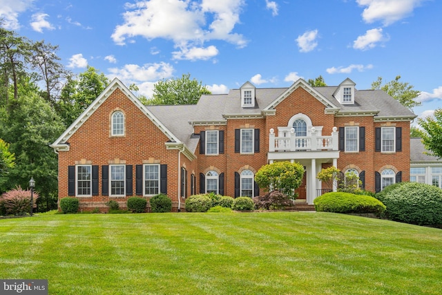 colonial home featuring a balcony and a front lawn