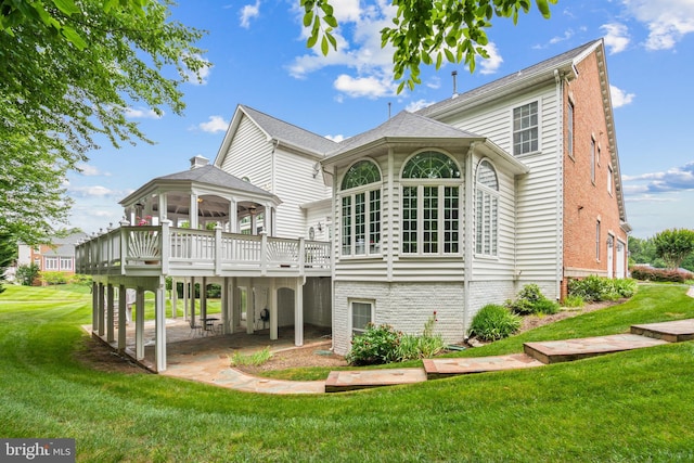 rear view of property with a wooden deck, a yard, and a patio