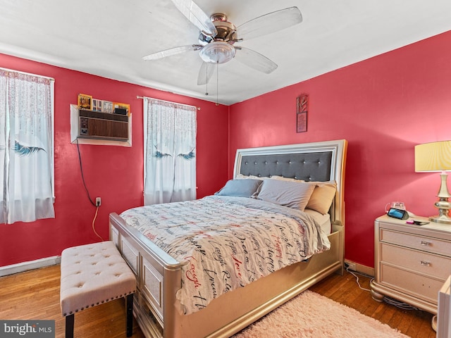 bedroom with ceiling fan, dark wood-type flooring, and a wall unit AC