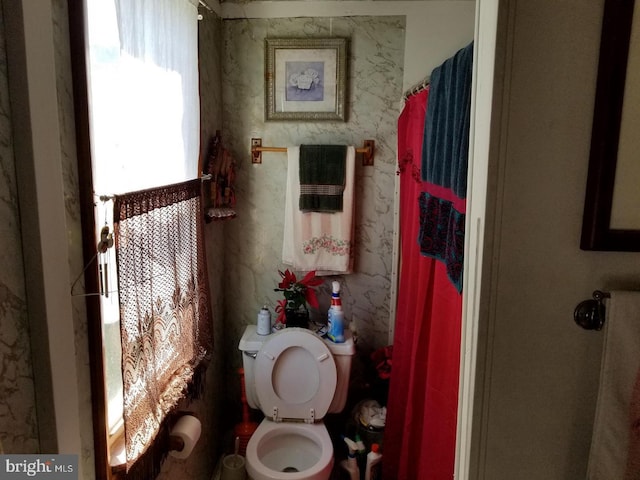 bathroom featuring toilet and curtained shower