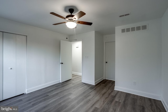 unfurnished bedroom with ceiling fan, a closet, and dark wood-type flooring