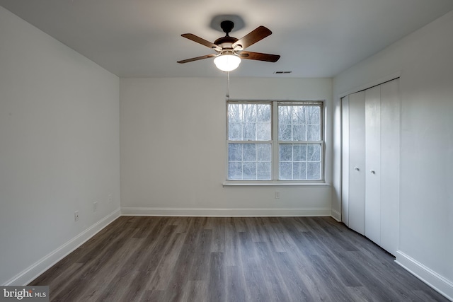 unfurnished bedroom featuring ceiling fan, dark hardwood / wood-style flooring, and a closet