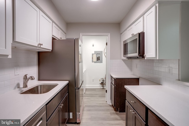 kitchen featuring appliances with stainless steel finishes, white cabinetry, tasteful backsplash, and sink