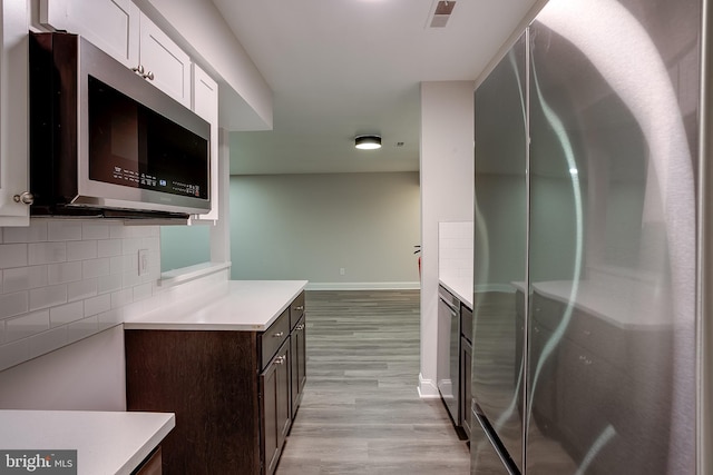 kitchen featuring backsplash, light hardwood / wood-style floors, fridge, white cabinetry, and dark brown cabinets