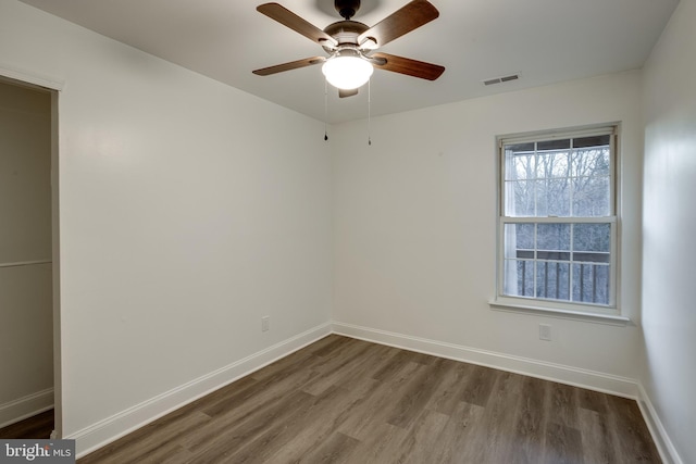 empty room with ceiling fan and dark hardwood / wood-style flooring