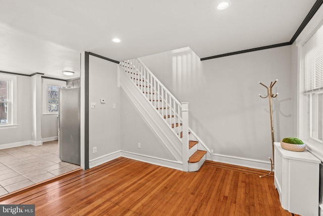 stairs with hardwood / wood-style flooring and ornamental molding