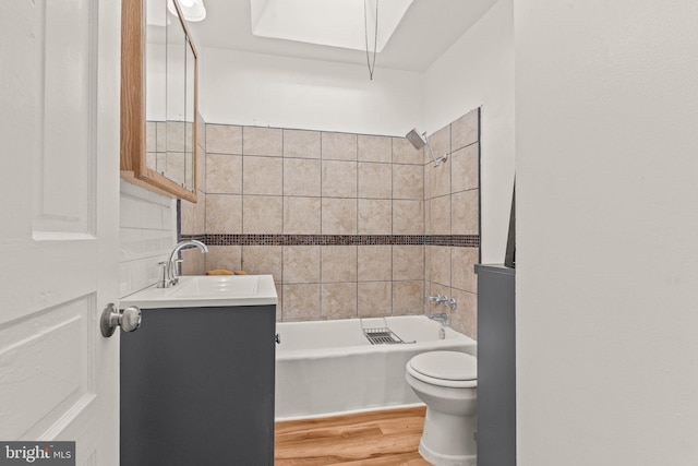 full bathroom featuring tiled shower / bath, hardwood / wood-style flooring, vanity, and toilet