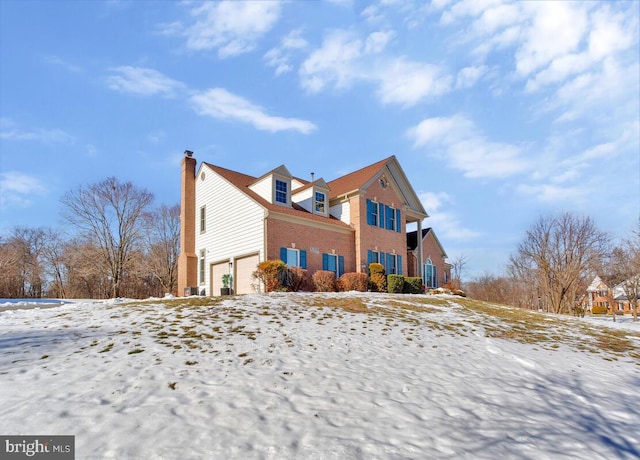 snow covered property with a garage