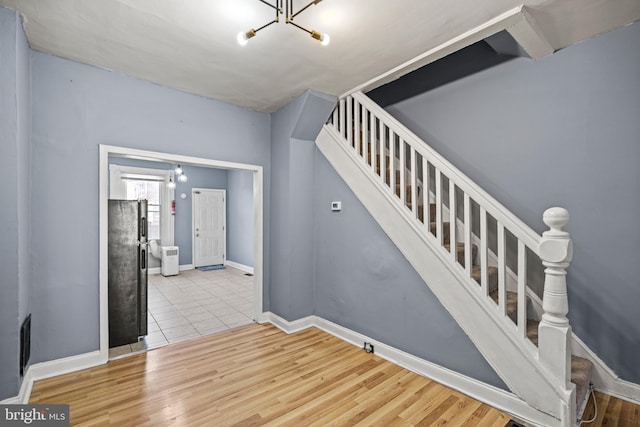 staircase with an inviting chandelier and hardwood / wood-style flooring