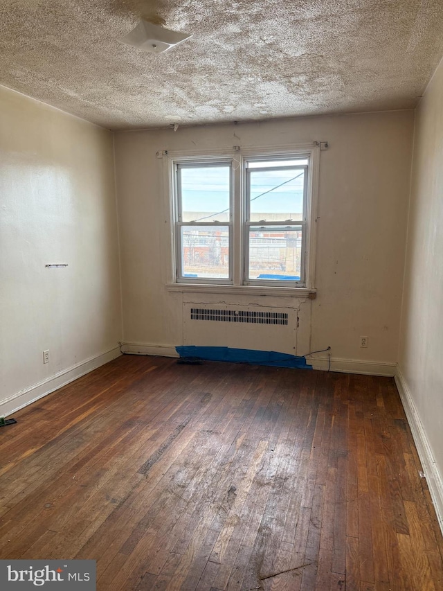 unfurnished room with a textured ceiling, radiator, and dark hardwood / wood-style flooring