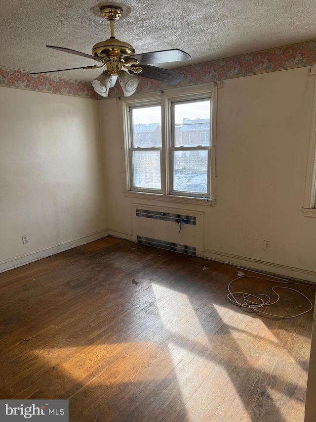 unfurnished room featuring ceiling fan, dark wood-type flooring, radiator heating unit, and a textured ceiling