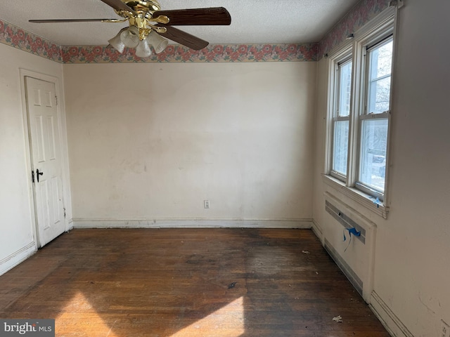 unfurnished room with ceiling fan, dark wood-type flooring, and a textured ceiling