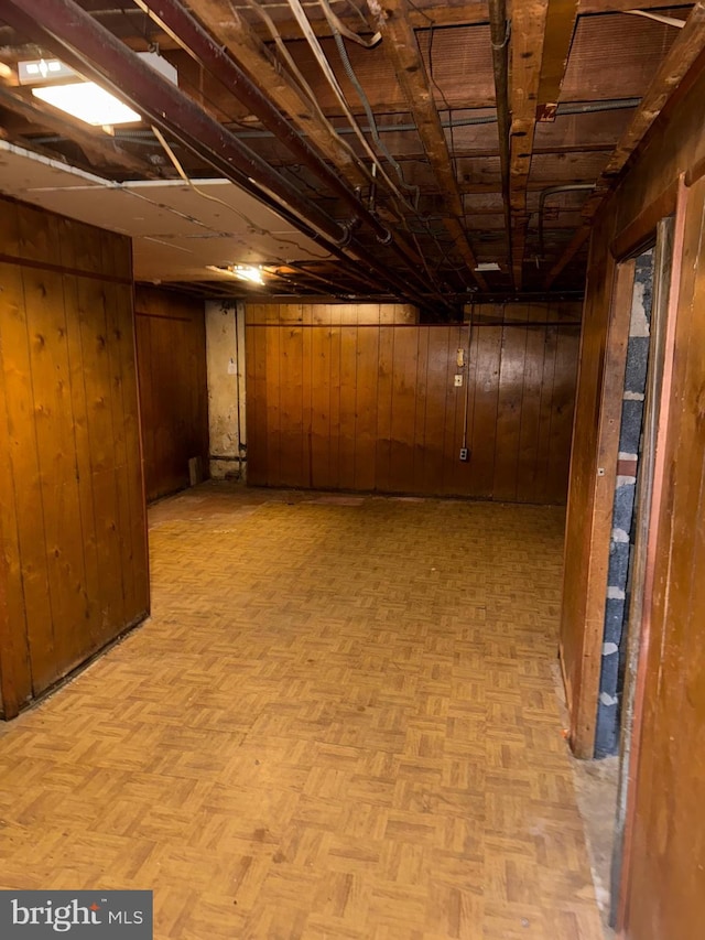 basement featuring light parquet floors and wood walls