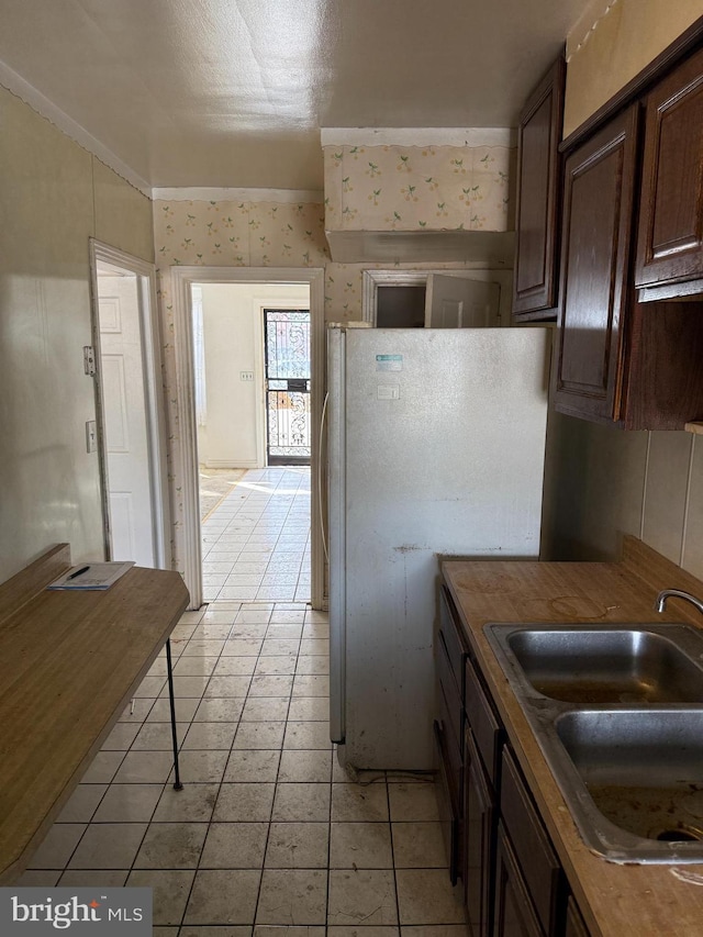 kitchen with white refrigerator, dark brown cabinets, wooden counters, and sink