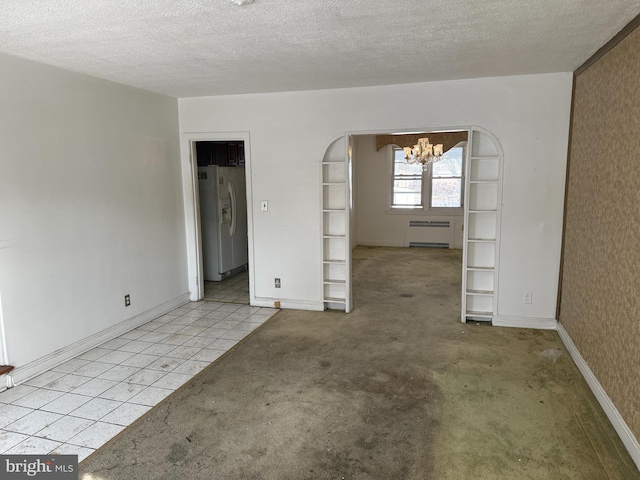 spare room featuring a chandelier, light tile patterned flooring, and a textured ceiling