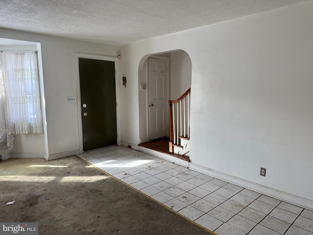 carpeted foyer with a textured ceiling