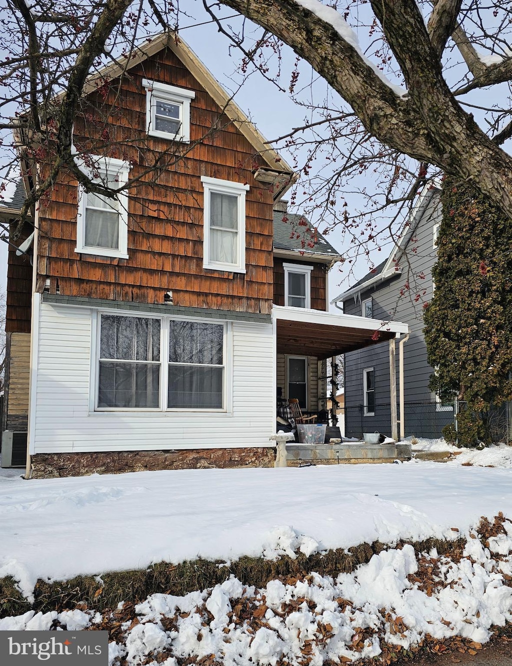 snow covered rear of property with central AC