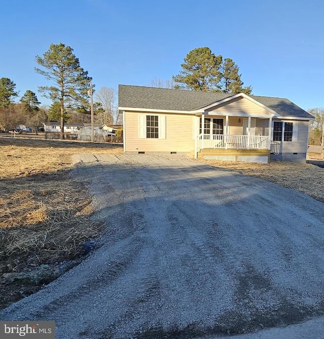 view of front of property featuring covered porch, driveway, a shingled roof, and crawl space