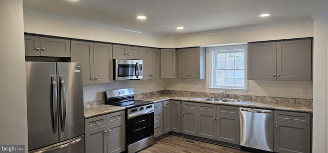 kitchen featuring appliances with stainless steel finishes, a sink, gray cabinetry, and ornamental molding