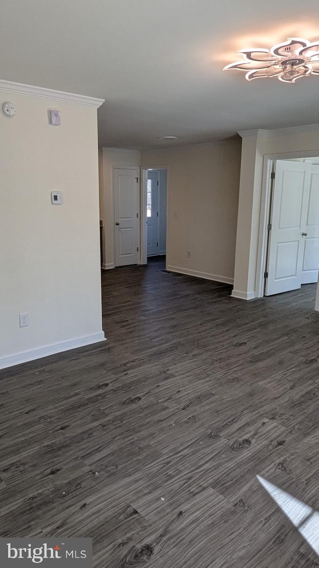 unfurnished room with ornamental molding, dark wood-style flooring, and baseboards