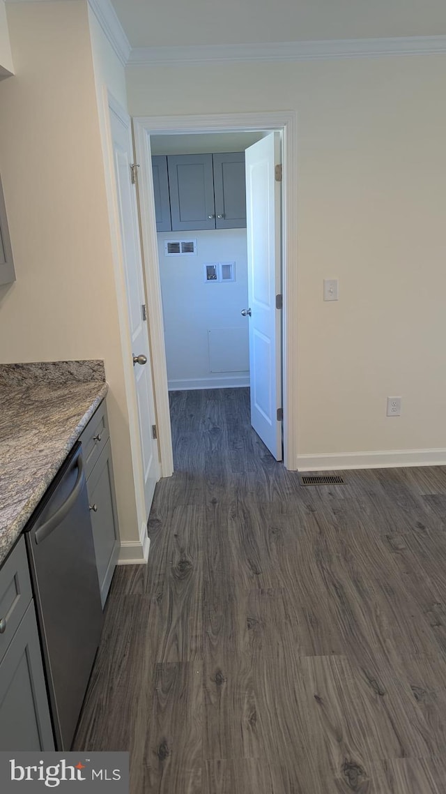 interior space with dark wood-style flooring, washer hookup, baseboards, ornamental molding, and cabinet space