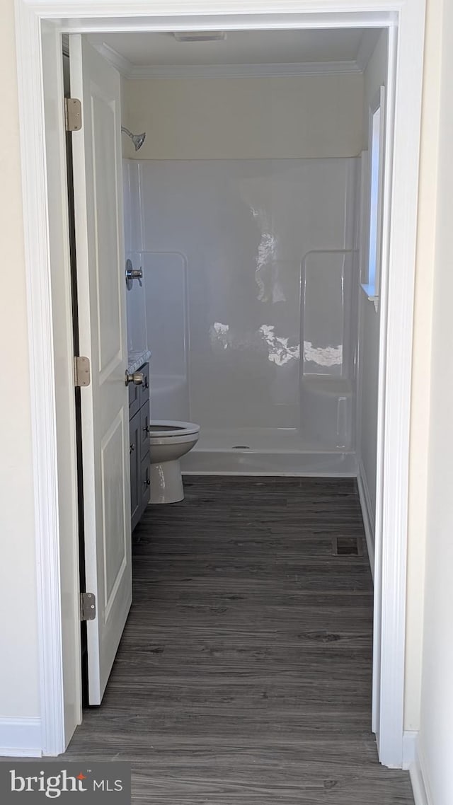 bathroom featuring a walk in shower, wood finished floors, toilet, and crown molding