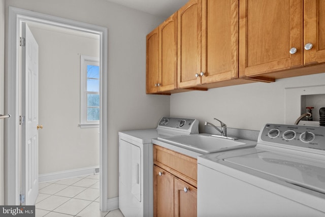 laundry area with sink, light tile patterned floors, cabinets, and separate washer and dryer