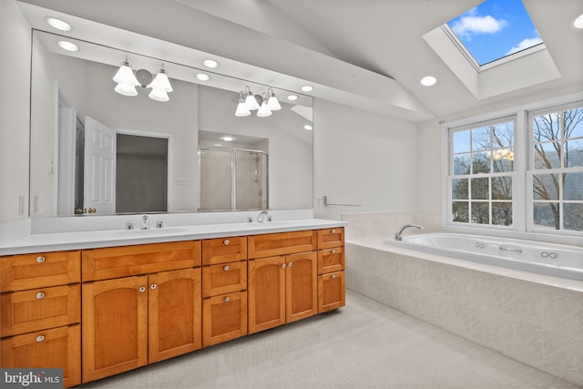 bathroom with independent shower and bath, vanity, and lofted ceiling with skylight