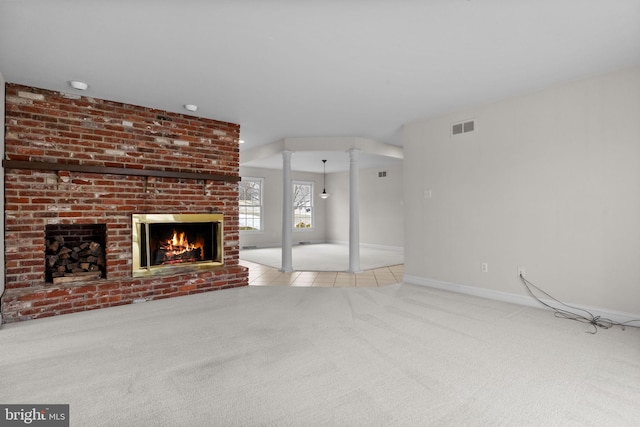 unfurnished living room with light colored carpet, ornate columns, and a fireplace