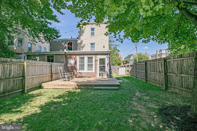 rear view of property featuring a lawn and a deck