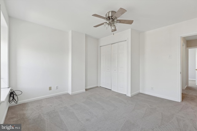 unfurnished bedroom featuring ceiling fan, a closet, and light carpet