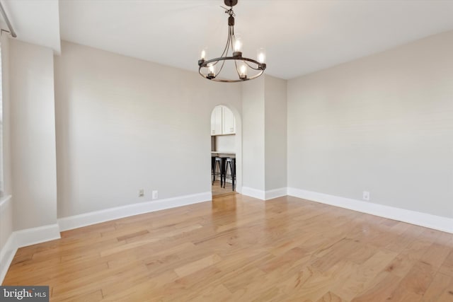 unfurnished room featuring light wood-type flooring and a chandelier