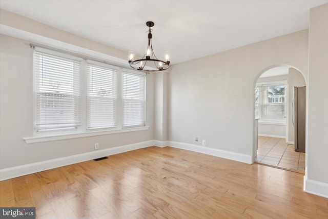 unfurnished dining area with an inviting chandelier and light hardwood / wood-style flooring