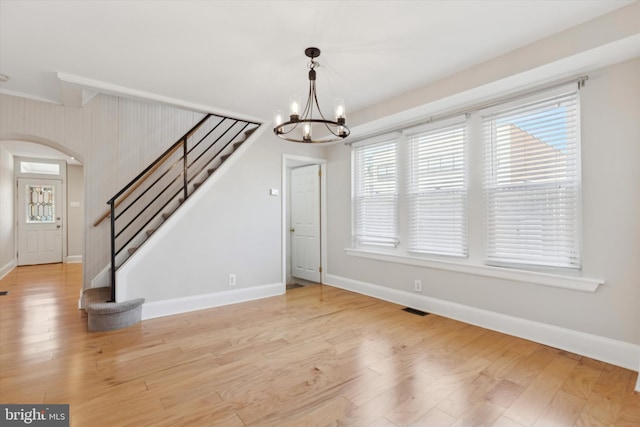 interior space featuring beamed ceiling, light wood-type flooring, plenty of natural light, and a notable chandelier