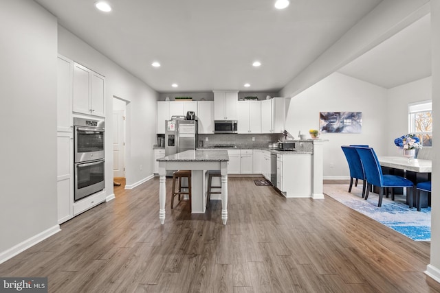 kitchen featuring stainless steel appliances, white cabinetry, and light stone countertops