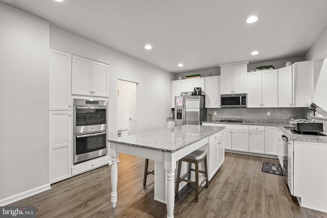 kitchen with light stone counters, white cabinets, appliances with stainless steel finishes, and a kitchen island